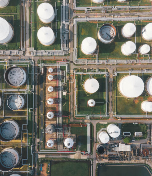 Aerial view morning time of petro chemical plant and oil refinery, power plant working with crude oil Storage tank at sunrise near mountain green environment concept