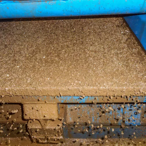 Shale shaker screen close up view with drill cutting flow out from oil base mud