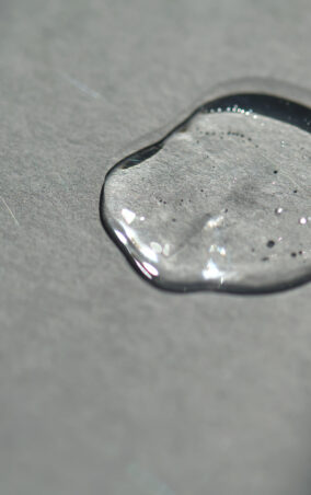 Pipette with spilled cosmetic oil or serum on a gray background.