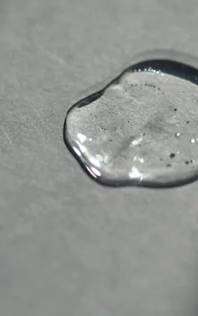 Pipette with spilled cosmetic oil or serum on a gray background.