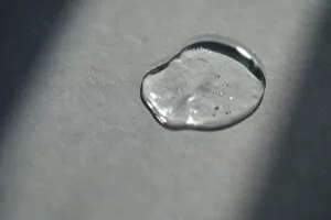 Pipette with spilled cosmetic oil or serum on a gray background.